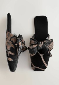 Schwarze Samt-Slipper mit floralem Muster in Rosatönen, geknotetem Vorderdesign, flacher Sohle und weichem Stoffgefühl.