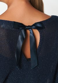 Marineblauer Strickpullover mit strukturiertem Muster, ausgestattet mit einem Schlüssellochdetail im Rücken, das mit einem Satinstreifen gebunden ist.
