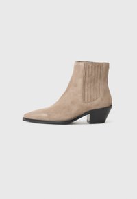 Stivale alla caviglia in suede beige con punta affusolata e tacco sagomato, caratterizzato da dettagli di cuciture verticali sui lati.
