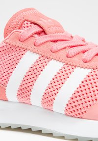 Rosa sneakers med meshtackning, vit tre-stripes design, texturerade snören och gummisula. Har en vadderad tunga och sydda detaljer.