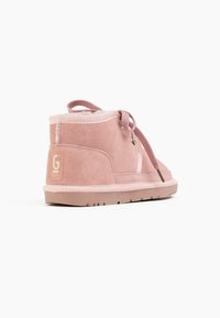 Stivaletti alla caviglia in suede rosa con una morbida fodera interna, dettagli di cuciture sottili e suole in gomma piane. Lacci e occhielli in metallo per la chiusura.