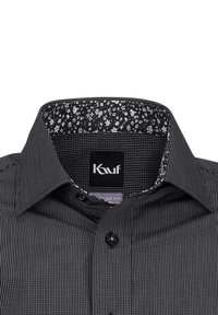 La camicia a scacchi bianco e nero presenta un colletto nero solido con fodera a stampa floreale. Include un'etichetta logo e un design a vestibilità normale.
