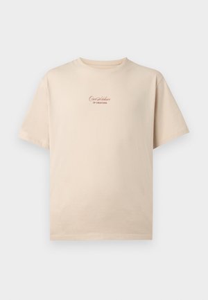 Beigen värinen lyhythihainen t-paita, jossa teksti "Our Archive of Creations" painettuna pienellä käsinkirjoitusfontilla rinnan keskellä.