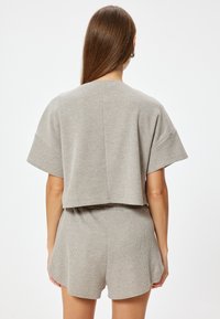 Lichtgrijze, geribde katoenen twee-delige set met een cropped top en shorts. Heeft ontspannen mouwen en een tailleband voor comfort.