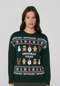 Dunkelgrüner Strickpullover mit festlichen Motiven: Schneemänner, Rentiere, Lebkuchenmänner, Santa und dem Text "WEIHNACHTS-TEAM". Weicher Stoff.