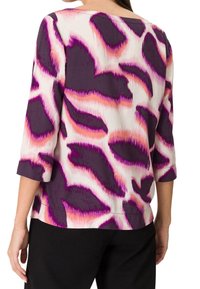 Langärmliges Oberteil aus leichtem Stoff mit einem abstrakten Muster in Lila, Pink und Weiß. Runder Halsausschnitt und lockere Passform. Weiche Textur.