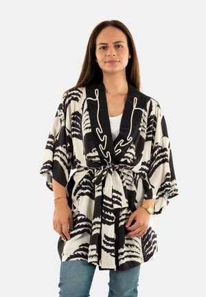 Kimono à motif noir et blanc avec col châle, taille nouée et manches fluides, fabriqué en tissu léger avec une finition brillante.