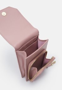 Portafoglio in pelle rosa con hardware dorato. Presenta più scomparti, una tasca con zip e una chiusura a scatto. Texture liscia.