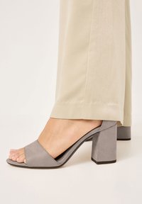Graue Absatzsandalen mit offenem Zehenbereich, aus einem glatten, wildlederähnlichen Material, mit einem breiten, sich überlappenden Riemen und einem klobigen, quadratischen Absatz.