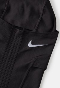 Top atlético preto com um acabamento texturizado, apresentando um proeminente logo em forma de swoosh branco da Nike e linhas de design estruturadas ao longo do tecido.