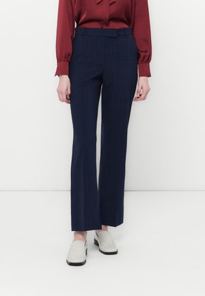 Navy plaid trousers with a straight-leg design, featuring a flat front and side pockets. Worn with a burgundy blouse and grey slip-on shoes.