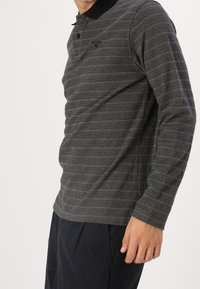 Graues Langarm-Polohemd mit horizontalen Streifen, ausgestattet mit einem schwarzen Kragen und einer Knopfleiste mit zwei Knöpfen, gefertigt aus einem strukturierten Stoff.