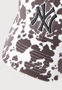 Καπέλο με μοτίβο καφέ και λευκής αγελάδας, με μαύρο κεντημένο λογότυπο, κυρτή γείσο και ορατές ραφές. Μαλακή υφή υφάσματος.