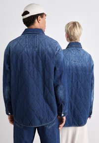 Jeansjakker i mørkeblå med quiltet mønster, knappelukking og synlig søm. En teksturert estetikk kompletterer begge stiler.