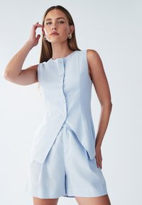 Hele sinine, hakkega varrukateta rõivas, mis sisaldab nööpidega särke madala kaelusega ja esialgsetest lühikestest pükstest. Sile kangas pehme tekstuuriga.