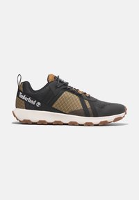 Zapatilla deportiva negra con parte superior de malla y acentos en marrón. Presenta un panel textil con un patrón, suela de goma y cordones en contraste.