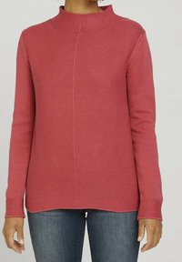 Red knitted sweater with a high neck, textured pattern, long sleeves, and a straight hem. Paired with blue jeans.