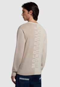 Maglione lavorato a maglia beige con una grande stampa verticale del logo sul retro. Il design include un collo rotondo e polsini a coste.