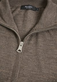 Rudos merino vilnos zip-up džemperis. Įrengtas aukštu apykakle ir sidabriniu užtrauktuku, pagamintas iš tekstūruoto audinio, viduje pažymėta dydis L.