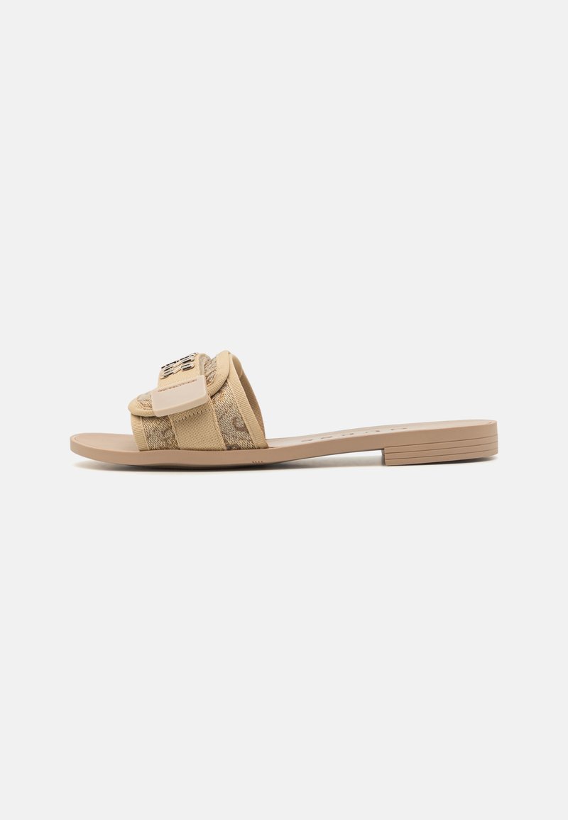 Sandal leve em bege com um superior texturizado e padrão, além de uma tira larga com detalhe em metal. Sola plana, design minimalista e estilo casual.