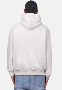 Übergroßer weißer Hoodie mit einer Kordelzugkapuze, gerippten Bündchen und Saum. Verfügt über eine glatte, matte Struktur und eine lockere Passform.