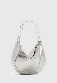Sac à main argenté avec une forme géométrique, en matériau brillant. Dispose d'une fermeture éclair et d'une sangle à maillons. Texture lisse.