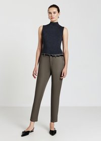 Ribbed dark gray sleeveless top paired with fitted olive-green trousers. Model accessorized with a black belt and black pointed-toe shoes.