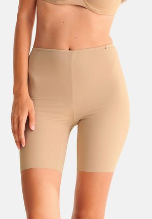 Shorts gainants taille haute beige portés par une personne, s'étendant de la taille au milieu de la cuisse, avec un tissu lisse et sans coutures.