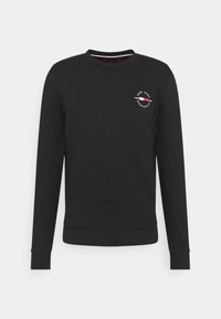 Sweatshirt noir à manches longues et col rond avec un petit logo circulaire blanc et rouge sur le côté gauche de la poitrine indiquant "New York Tommy Hilfiger MCMXLXIII".