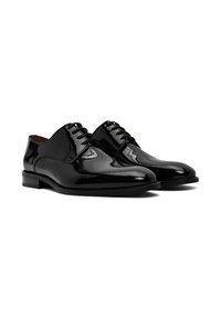 Chaussures habillées en cuir verni noir avec un bout arrondi, un design à lacets, une couture ton sur ton et un petit talon empilé. Fini lisse et brillant.