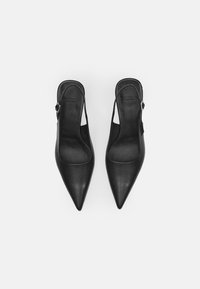Black leather slingback heels with pointed toe design, smooth texture, and silver hardware buckle. Features a minimalist style.