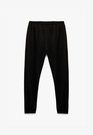 Zwarte sweatpants met een elastische tailleband, taps toelopend ontwerp en zachte textuur. Geen patronen of zichtbare hardware.