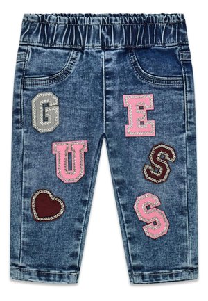 Pantalon en denim bleu pour tout-petit avec taille élastique et patchs décoratifs indiquant « GUESS » et une forme de cœur sur les jambes avant.