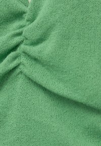 Grüner gestrickter Stoff mit einer strukturierten Oberfläche und leicht gerafften Details, die ein weiches und dehnbares Aussehen verleihen.