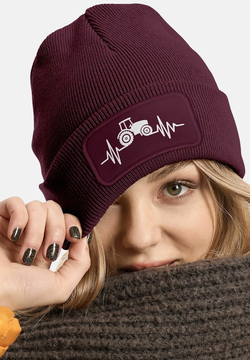 Maroon knit beanie with a stitched patch featuring a white tractor and heartbeat line design. Soft texture, snug fit, and casual style.
