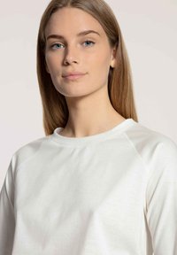 White sweatshirt made of soft material, featuring a crew neckline and raglan sleeves. Smooth texture with minimal visible stitching.