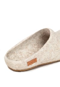 Beige Wollslipper mit einem strukturierten Filz-Obermaterial und einem tanfarbenen Leder-Label. Die Sohle ist flach und leicht konturiert.