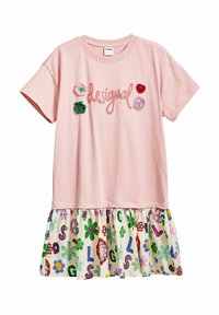 Rosa bomullströja med kort ärm och broderad "desigual" text. Den nedre delen har ett mönstrat, volangigt tyg med färgglada blommor.