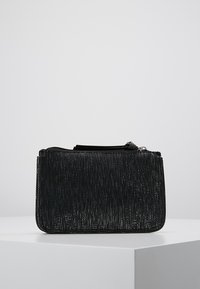 Svart rektangulär väska med vertikal metallisk textur. Har en blixtlåsstängning och en smal profil, lämplig för olika tillbehör eller nödvändigheter.