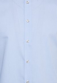 Camicia a quadretti piccoli azzurri e bianchi davanti con cinque bottoni bianchi allineati verticalmente.
