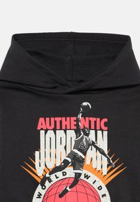 Μαύρη φούτερ μπλούζα με κουκούλα, που διαθέτει γραφιστικό σχέδιο ενό ς παίκτη μπάσκετ, με έντονο κόκκινο και λευκό κείμενο "AUTHENTIC JORDAN" και γραφικό σφαίρας.