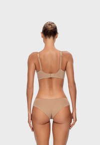 Beżowy, bezszwowy zestaw biustonosza i bikni wykonanego z gładkiej tkaniny. Regulowane ramiączka w biustonoszu. Minimalistyczny design bez wzorów i detali metalowych.