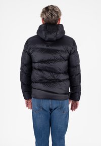 Doudoune noire avec capuche, présentant des sections matelassées verticales. Le matériau semble brillant et lisse, avec une texture douce.