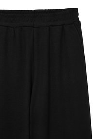 Pantalons de survêtement noirs en tissu texturé, dotés d'une taille élastique et de poches latérales, affichant une coupe décontractée et un design simple.