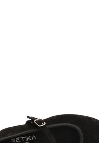 Zapato de ante negro con correa en el tobillo y hebilla plateada, punta redonda y forro interior suave. Diseño minimalista.