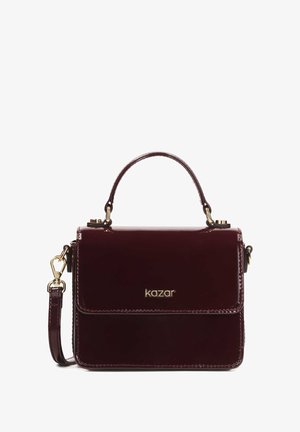 Burgundi színű patent bőr táska, rendezett formával, arany színű kiegészítőkkel, állítható vállpánttal és felső fogantyúval.
