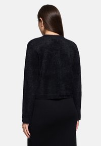Czarna krótka kurtka z teksturowanej, miękkiej tkaniny z długimi rękawami. Posiada okrągły dekolt i dopasowaną sylwetkę.