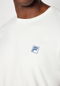 White short-sleeve t-shirt made of smooth fabric featuring a blue "F" logo in a square on the chest, round neckline, and relaxed fit.