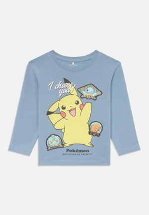 Chemise à manches longues bleue avec un graphique de Pikachu et le texte "Je te choisis !" ainsi que des badges Pokémon de différentes couleurs, en matériau en coton.