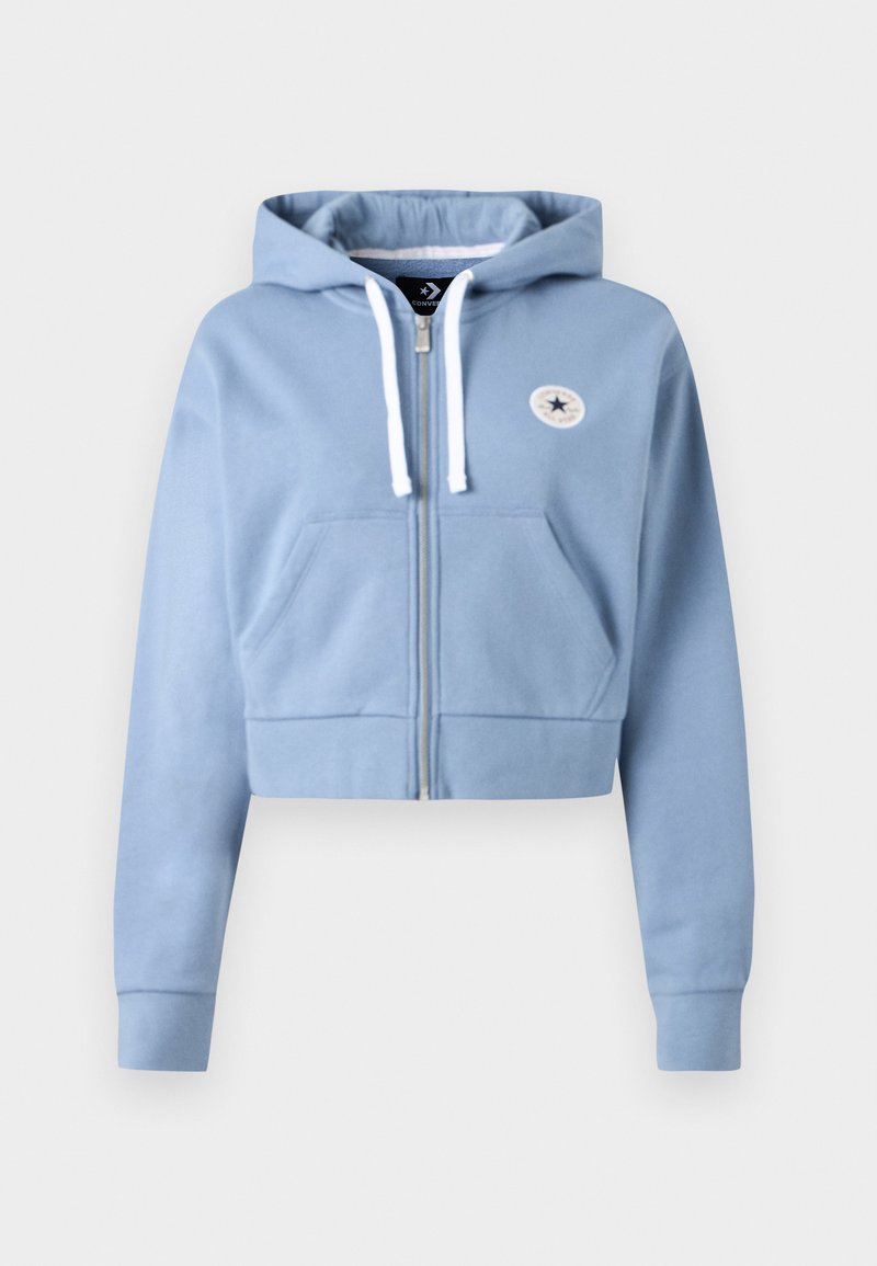 Sweat à capuche court bleu en tissu doux, équipé d'une fermeture éclair frontale, d'une capuche à cordon réglable et d'une poche avant avec un patch logo rond.